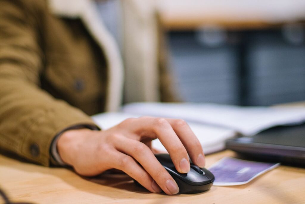 Focused shot of a hand operating a wireless mouse indoors at a desk.